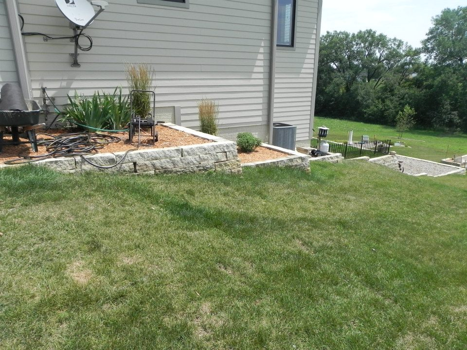 Lawn area transitioning to landscaped bed with stone edging and plants, illustrating effective landscape planning for outdoor spaces in Des Moines.