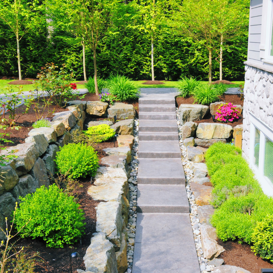 Backyard hardscaping featuring stone steps bordered by lush greenery and colorful flowers, illustrating landscaping design principles for enhancing outdoor spaces.