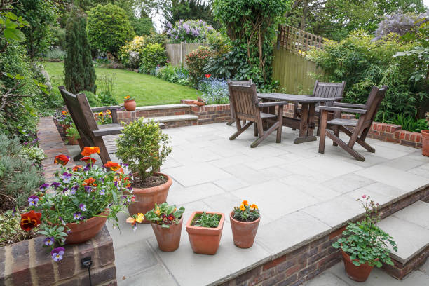 Patio area with wooden furniture, potted flowers, and a well-maintained garden, illustrating a comfortable outdoor space for family gatherings and relaxation.