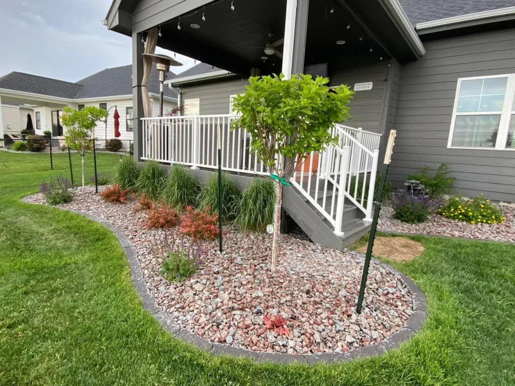 Landscaped yard featuring a modern home entrance, decorative gravel, and a variety of plants, illustrating the blend of contemporary design with natural elements.