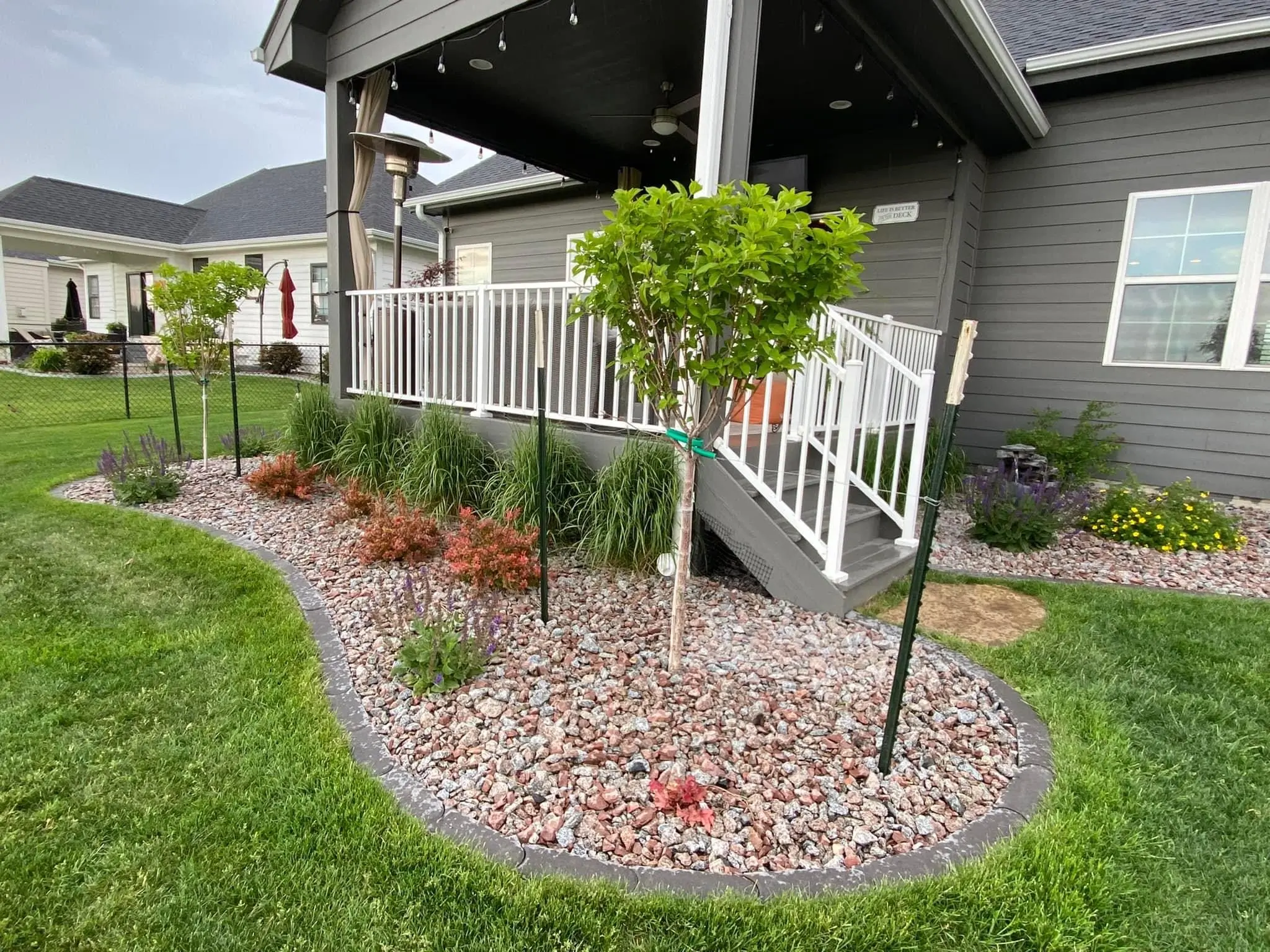 Landscaped garden with decorative rocks, shrubs, and a small tree near a house entrance, showcasing outdoor design elements for landscaping insights.