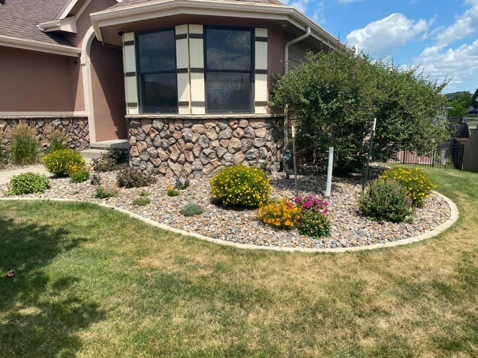 Landscaped garden area featuring colorful flowers and stone edging near a home, emphasizing aesthetic enhancement and stability for yard planning.